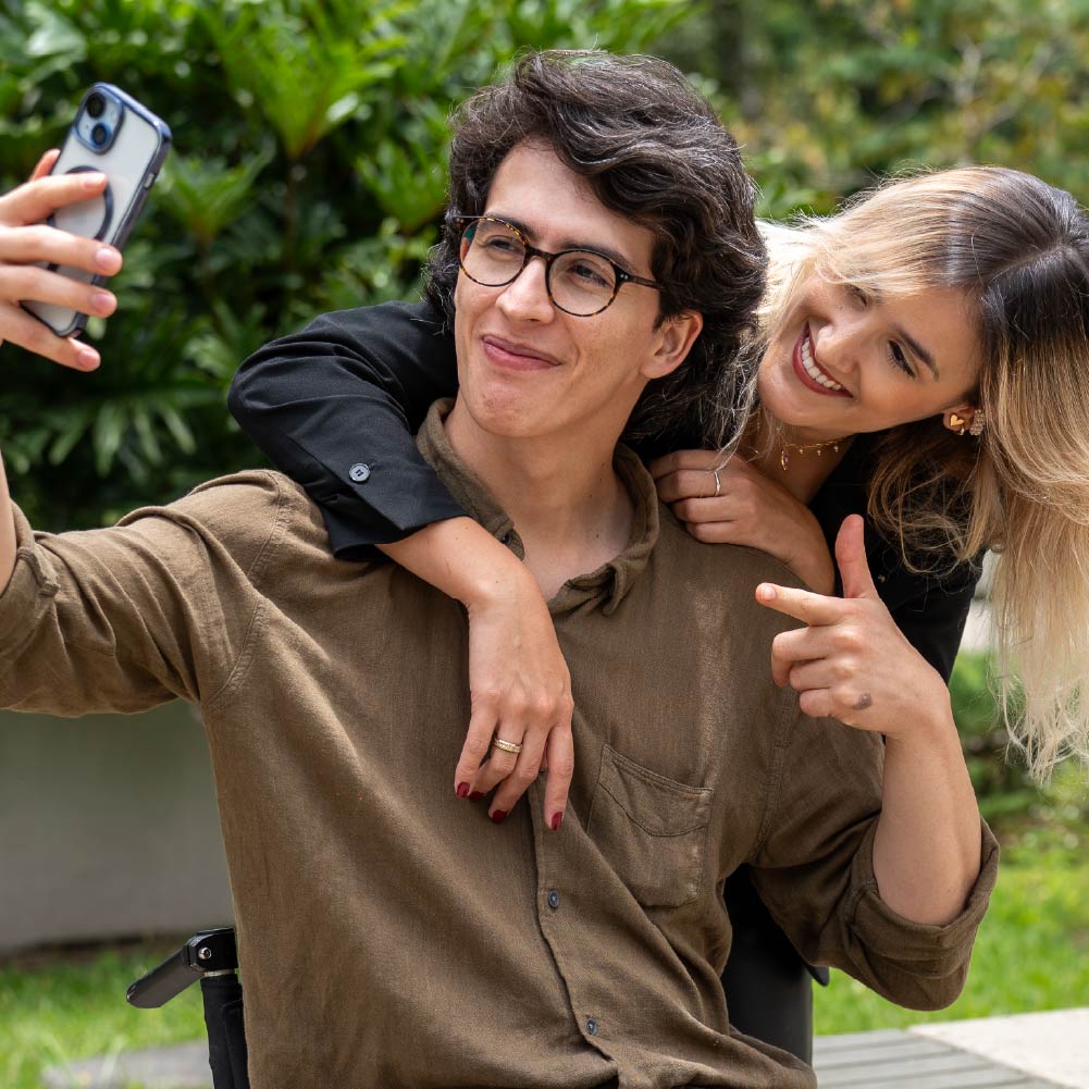 Joven colaborador de ISA, sonriendo abrazado por una de sus colegas, posando para una selfie.